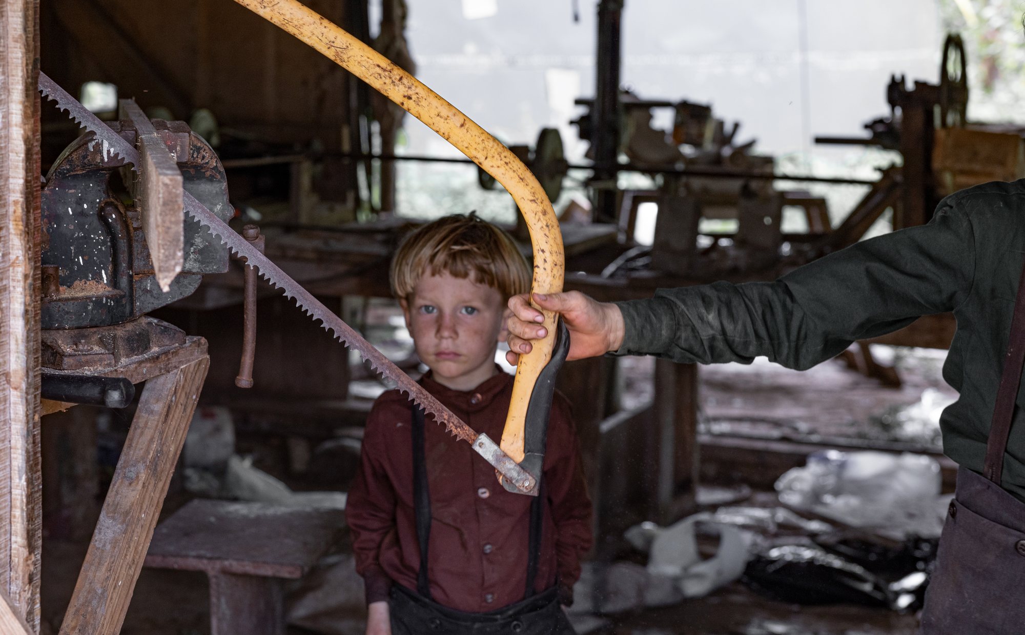 A boy and a man at a two-man saw in the workshop