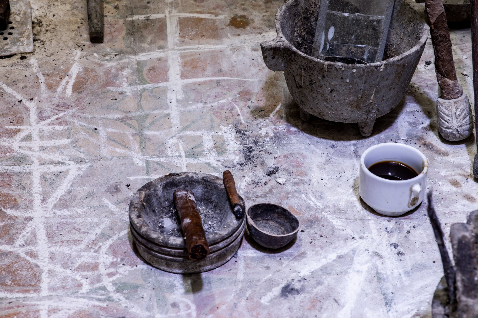 Stone mortars, a cup of dark coffee, and herbs on a worn tiled floor