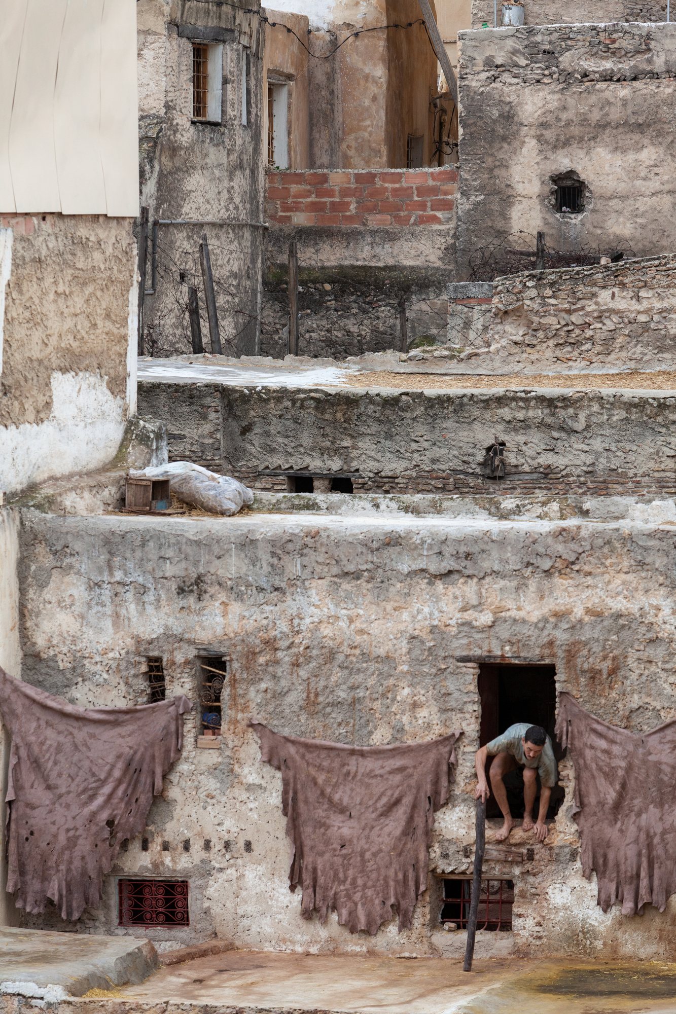 A worker emerges from a dark passage to the drying wall