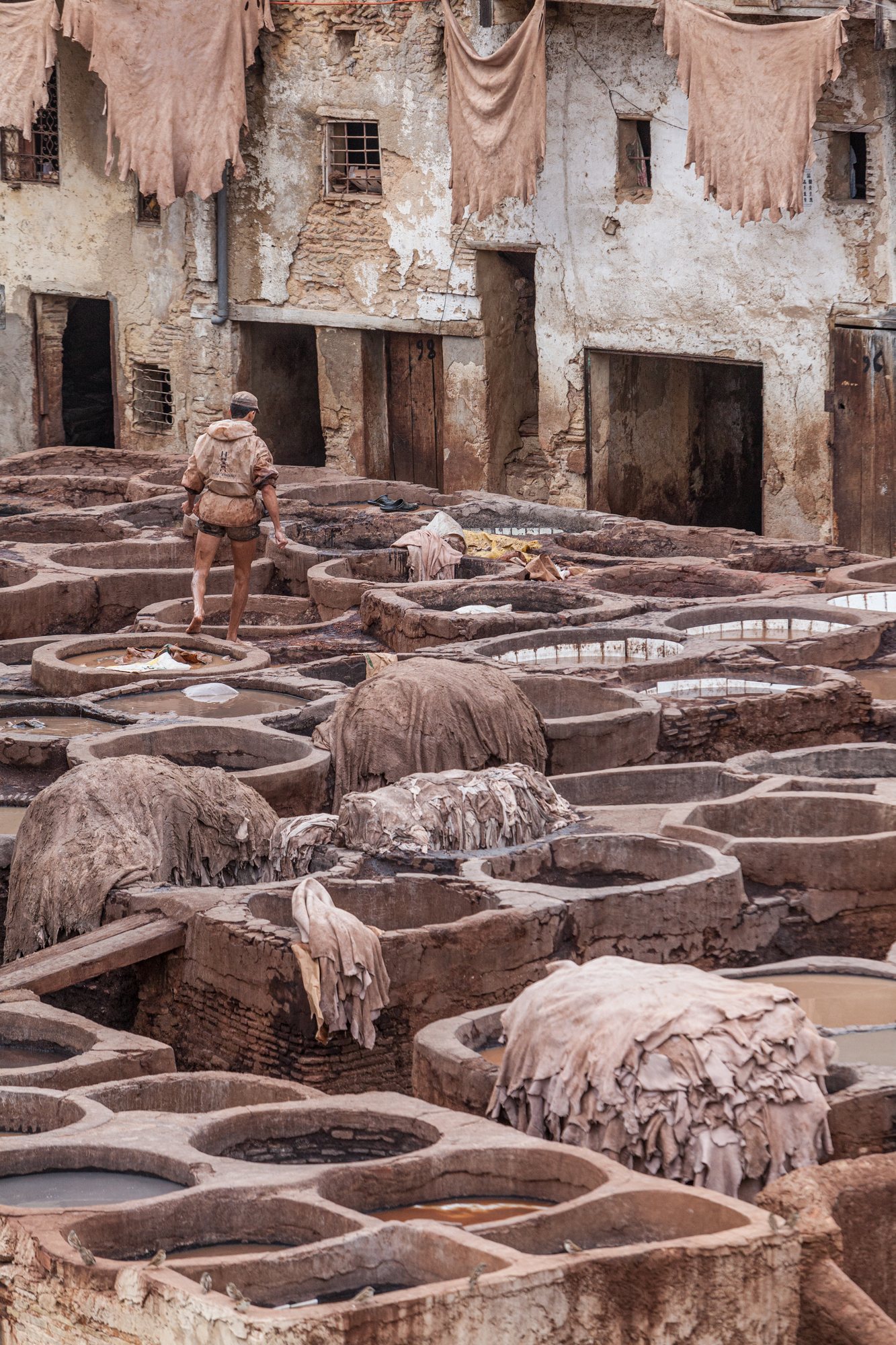 A worker crosses the stone rims between the vats