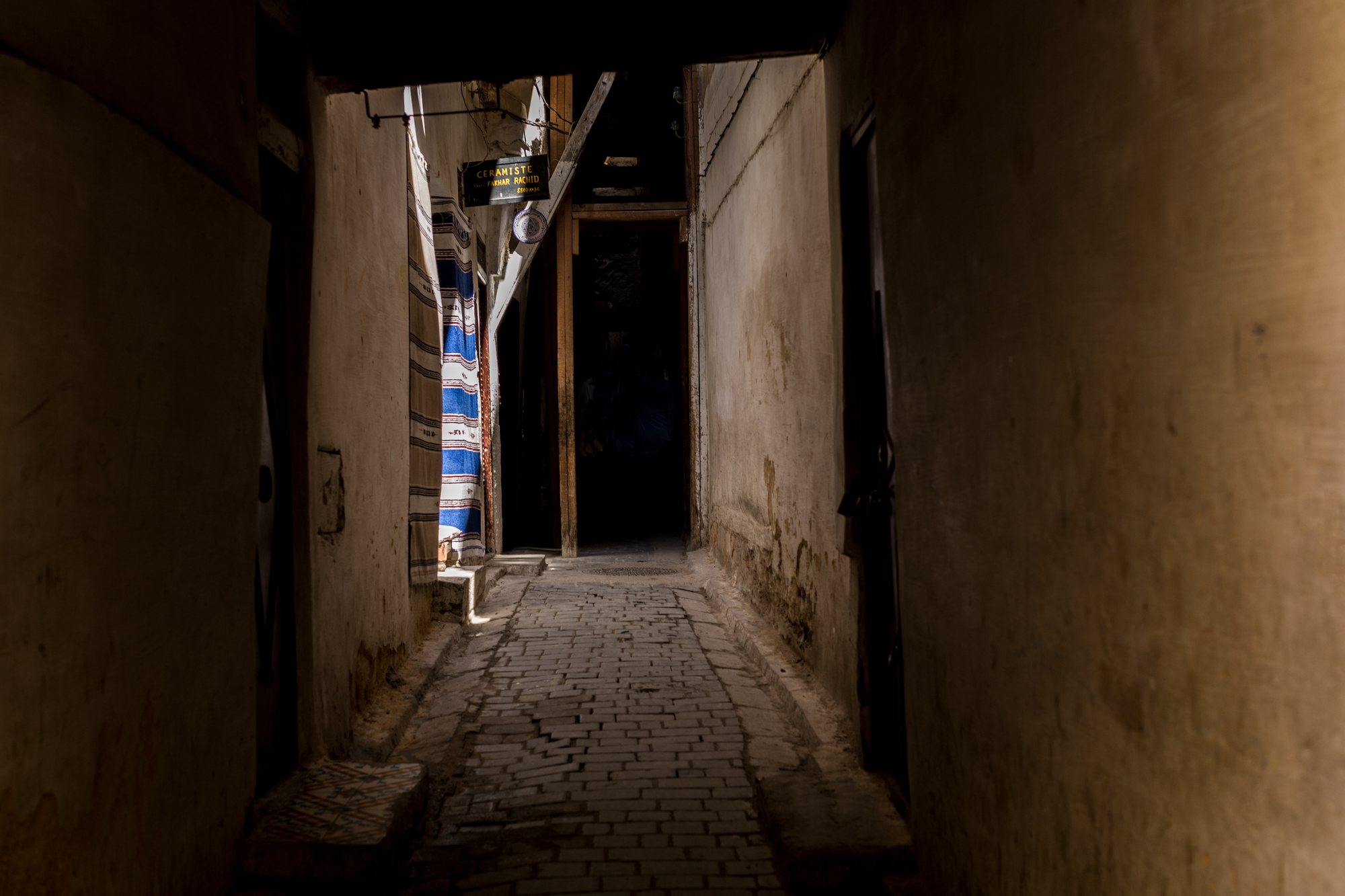 Rugs hung in the alley, a dark doorway behind