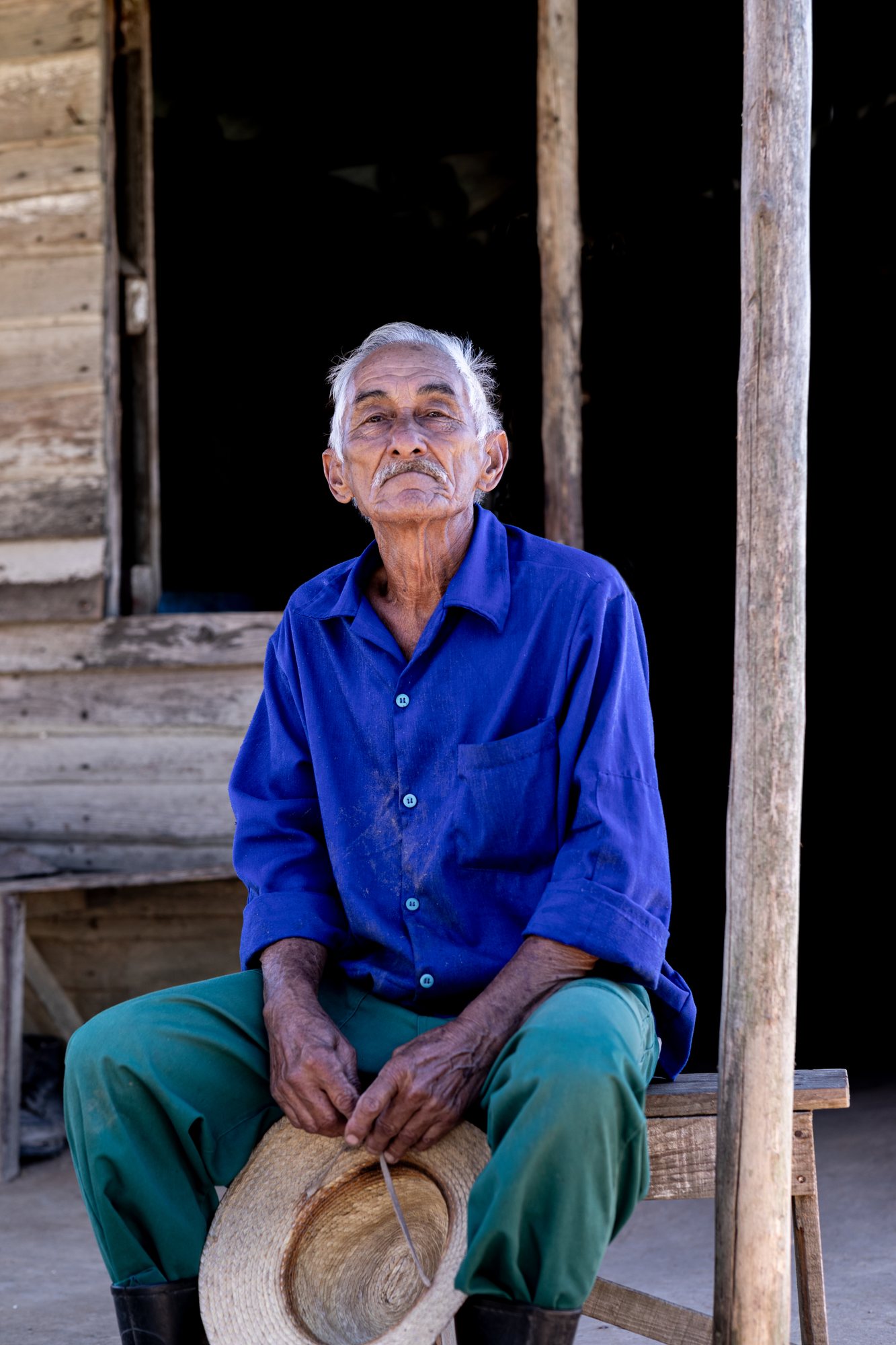 An elderly guajiro resting on the porch, his straw hat in his lap