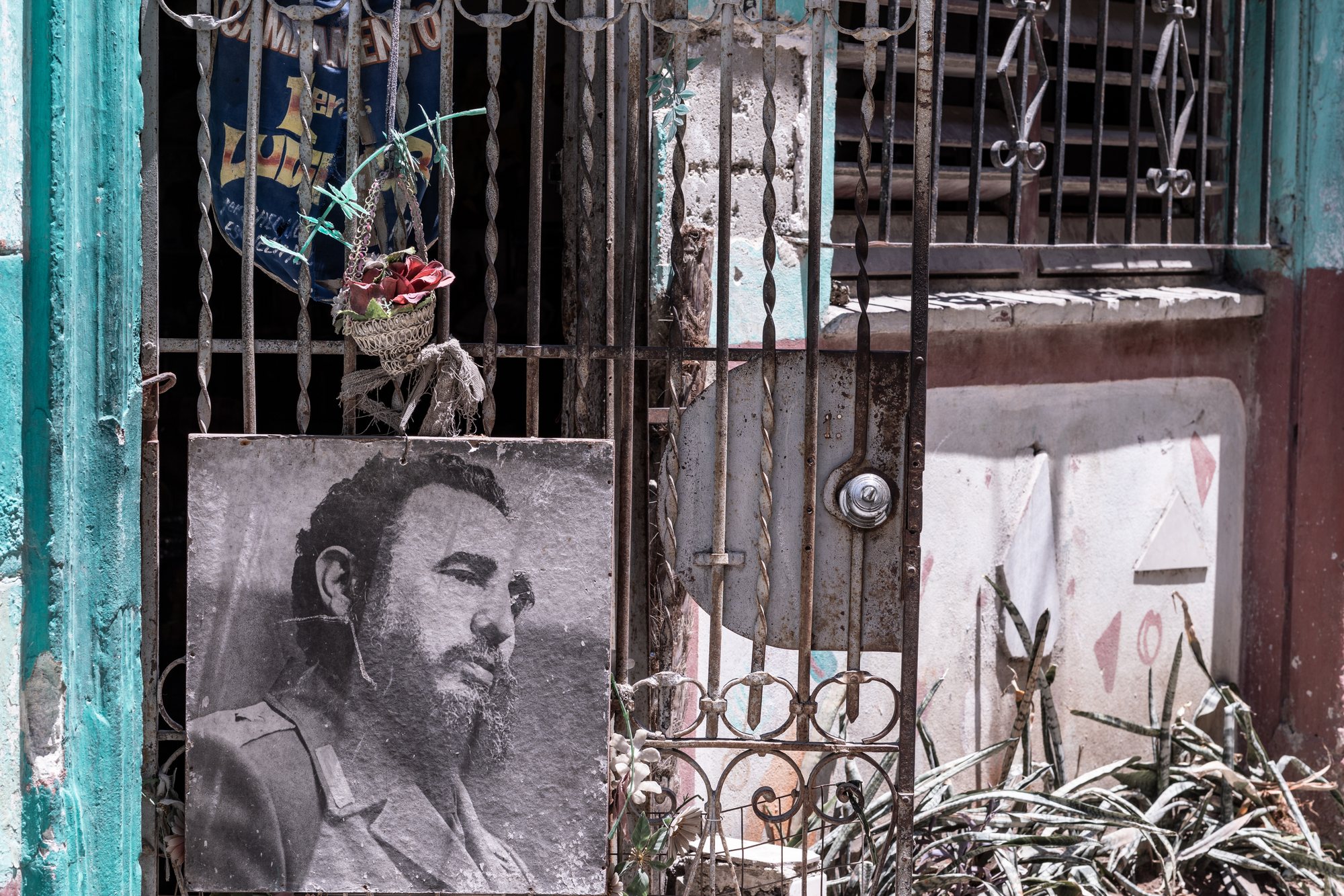 A weathered portrait of Fidel Castro behind the iron rejas