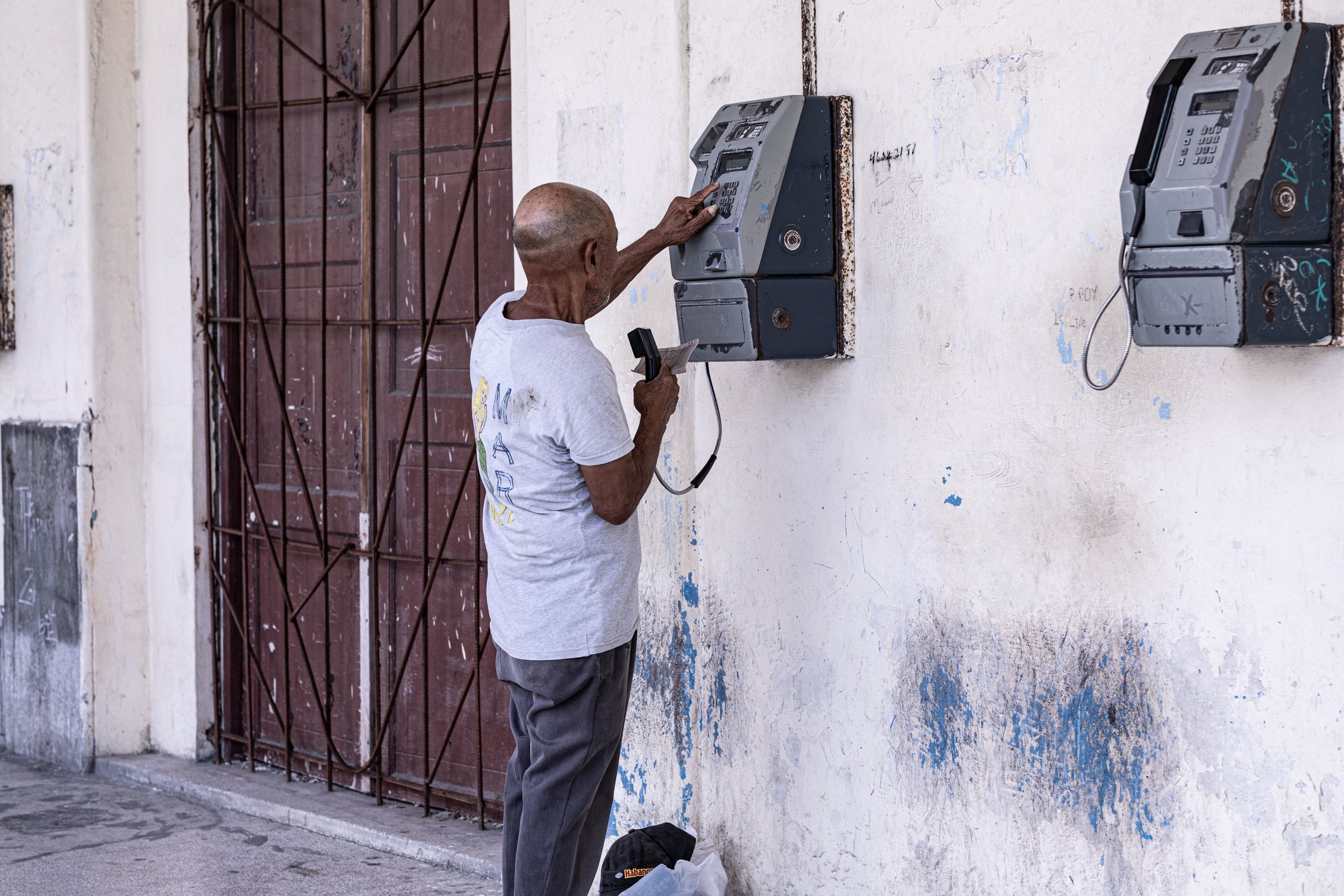 A man at an ETECSA payphone, card in hand