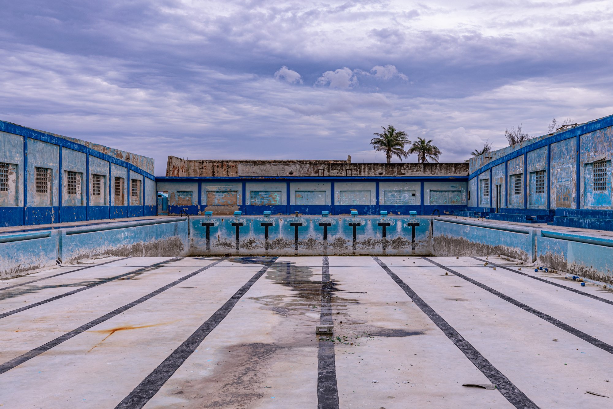An abandoned municipal pool, its lane lines still drawn