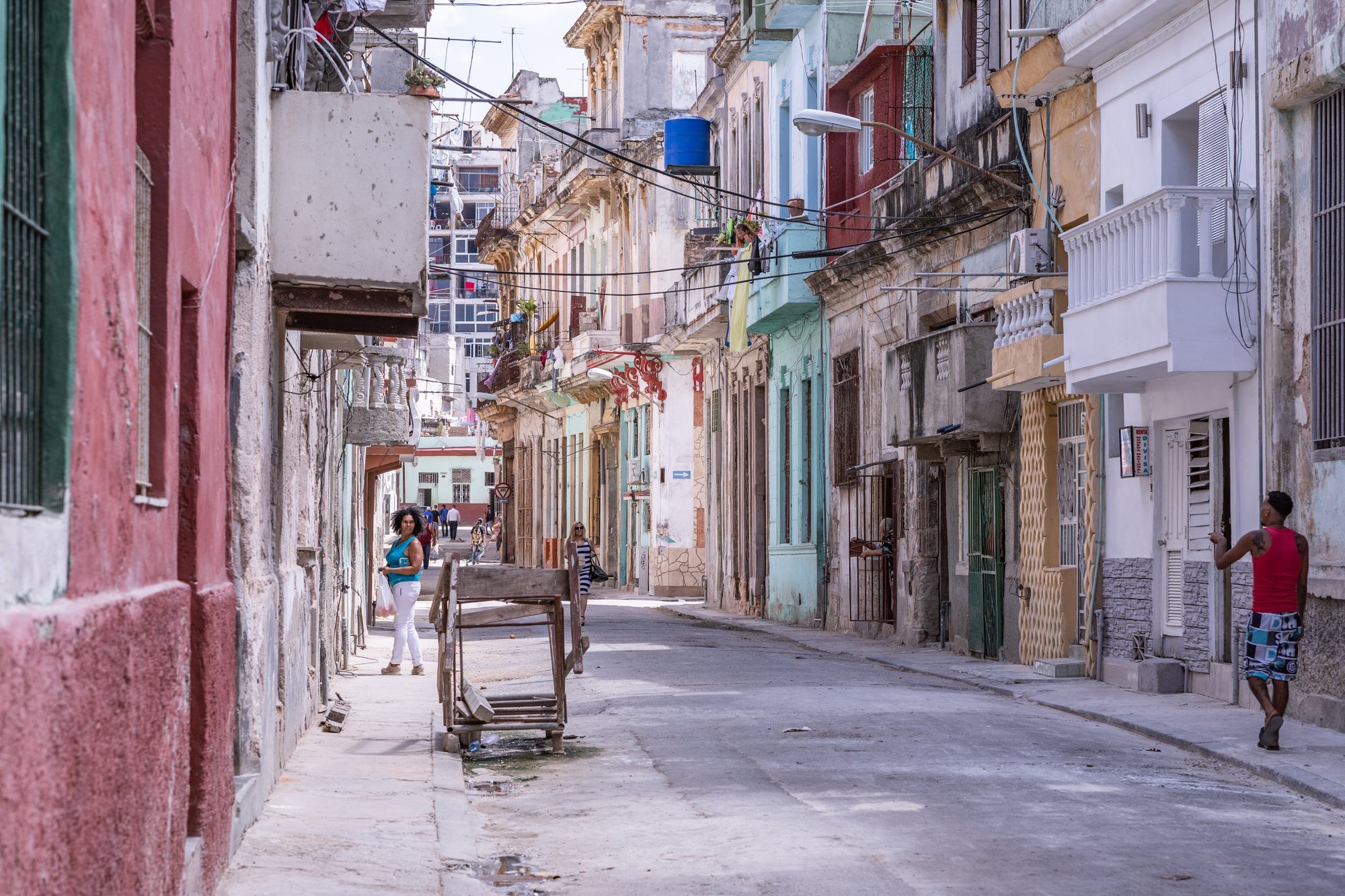 A woman walks a narrow, pastel street in the old city