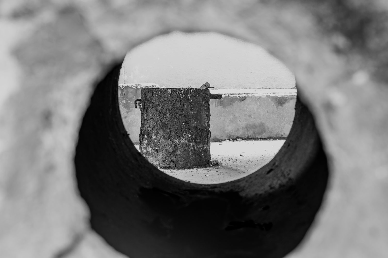 Monolith IV - a weathered rusted metal drum seen through a dark circular aperture, emphasizing decay and isolation
