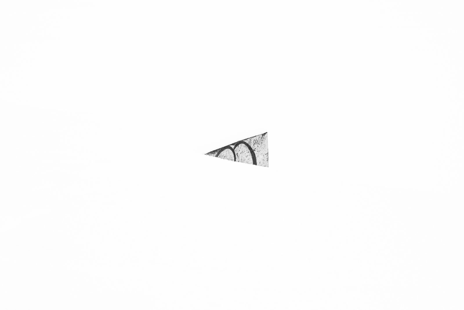 A weathered, graffiti-marked fragment of concrete isolated against bright snow