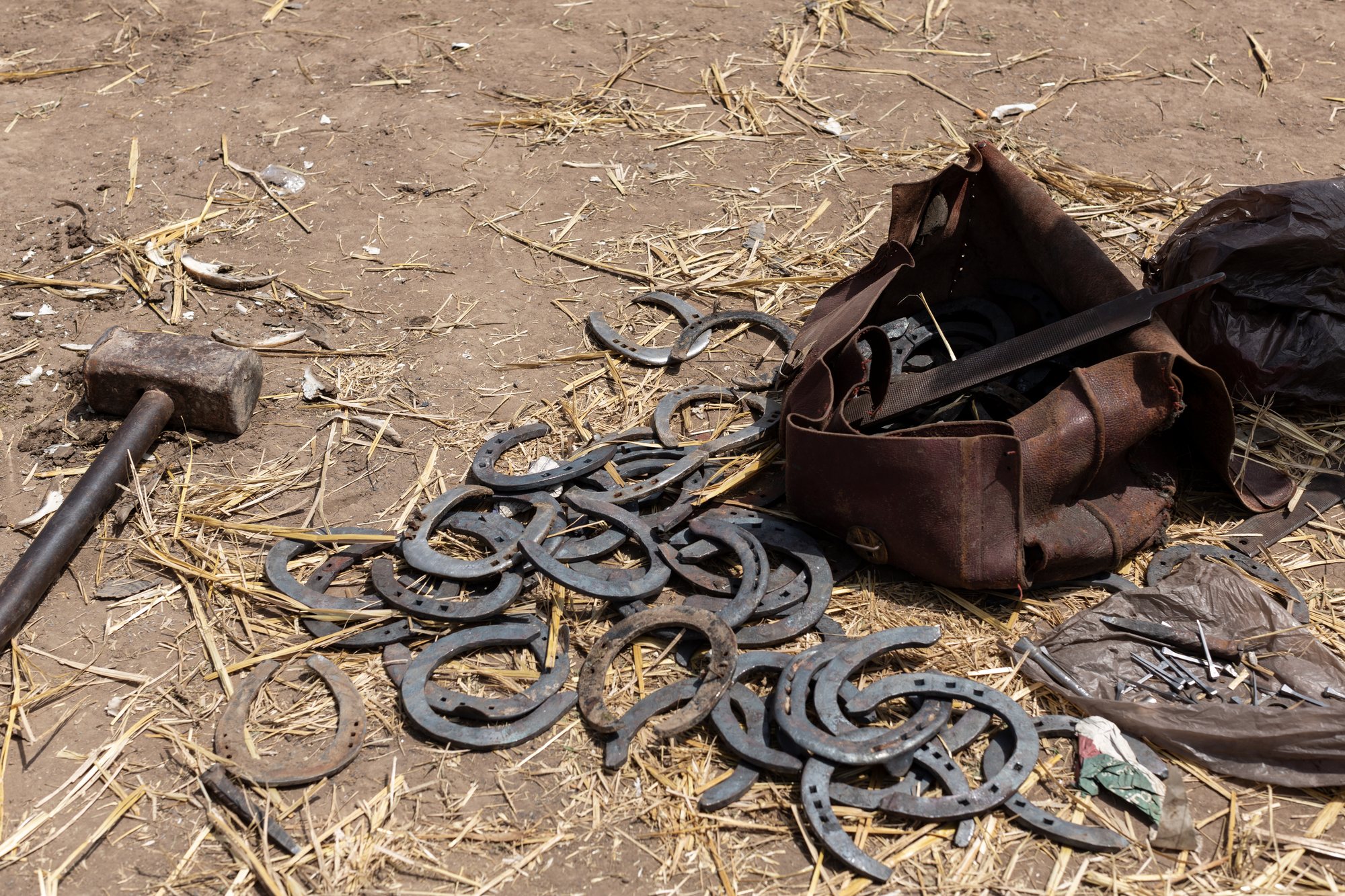 Horseshoes, a hammer and a leather kit on the dry ground